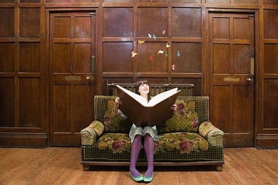 Menina no sofá lendo livro mágico gigante