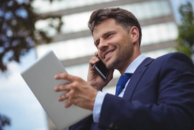 homem falando ao telefone com tablet na mão