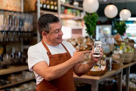 homem dentro do comércio mostrando seu celular