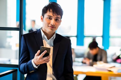 homem em um escritório segurando um celular