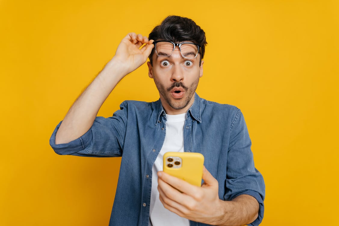 homem espantado com celular na mão