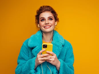 mulher segurando celular amarelo no fundo amarelo