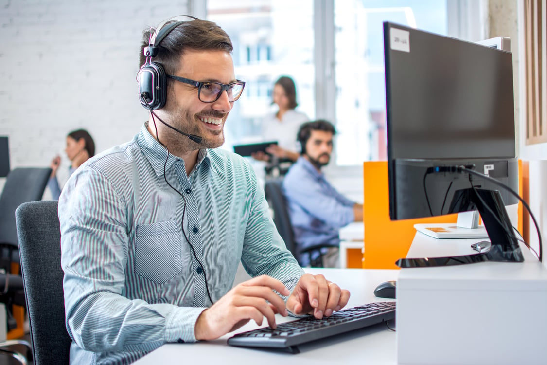 Homem de Telemarketing usando computador sorrindo