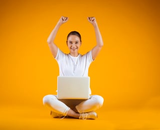 Mulher de branco comemorando e com computador no colo