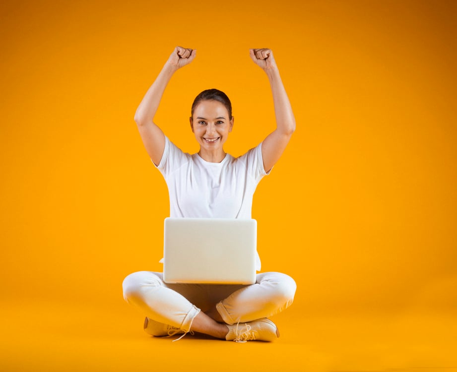 Mulher de branco comemorando e com computador no colo