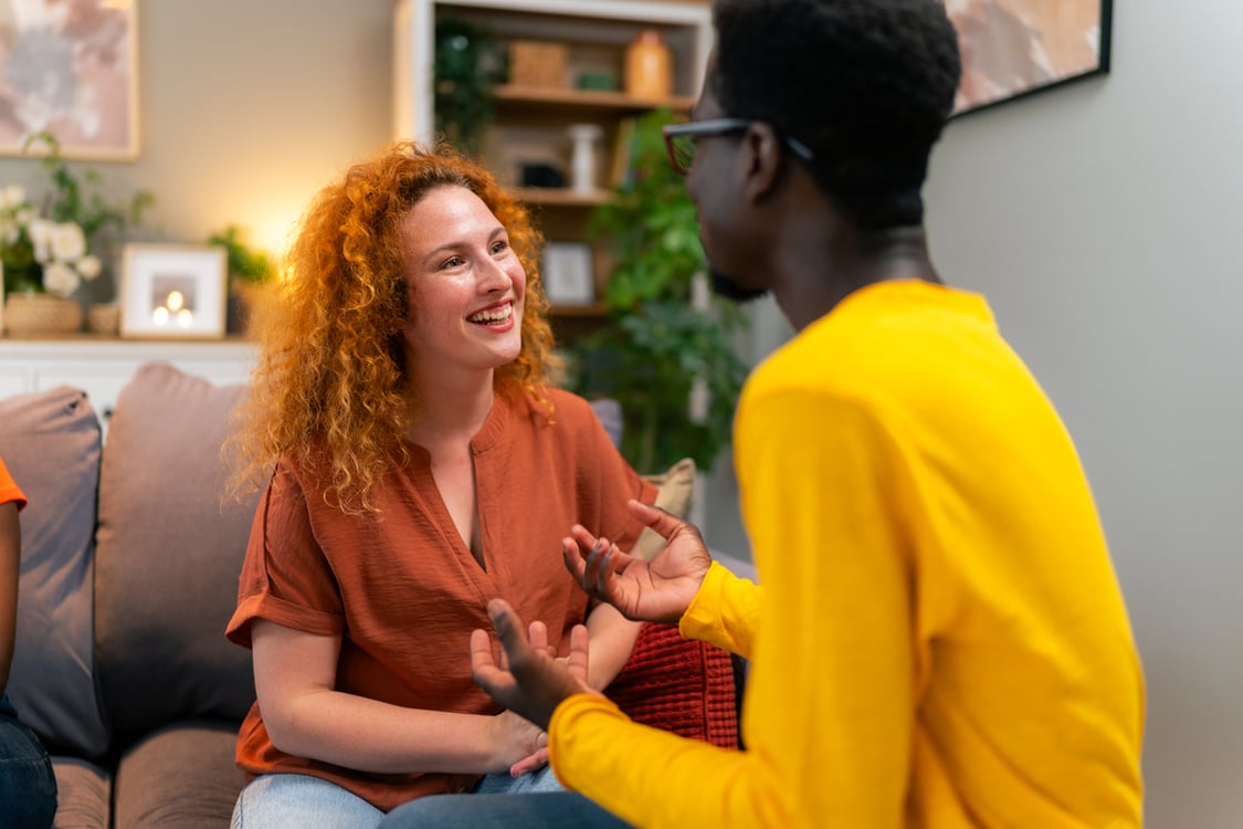 duas pessoas conversando na sala de uma casa