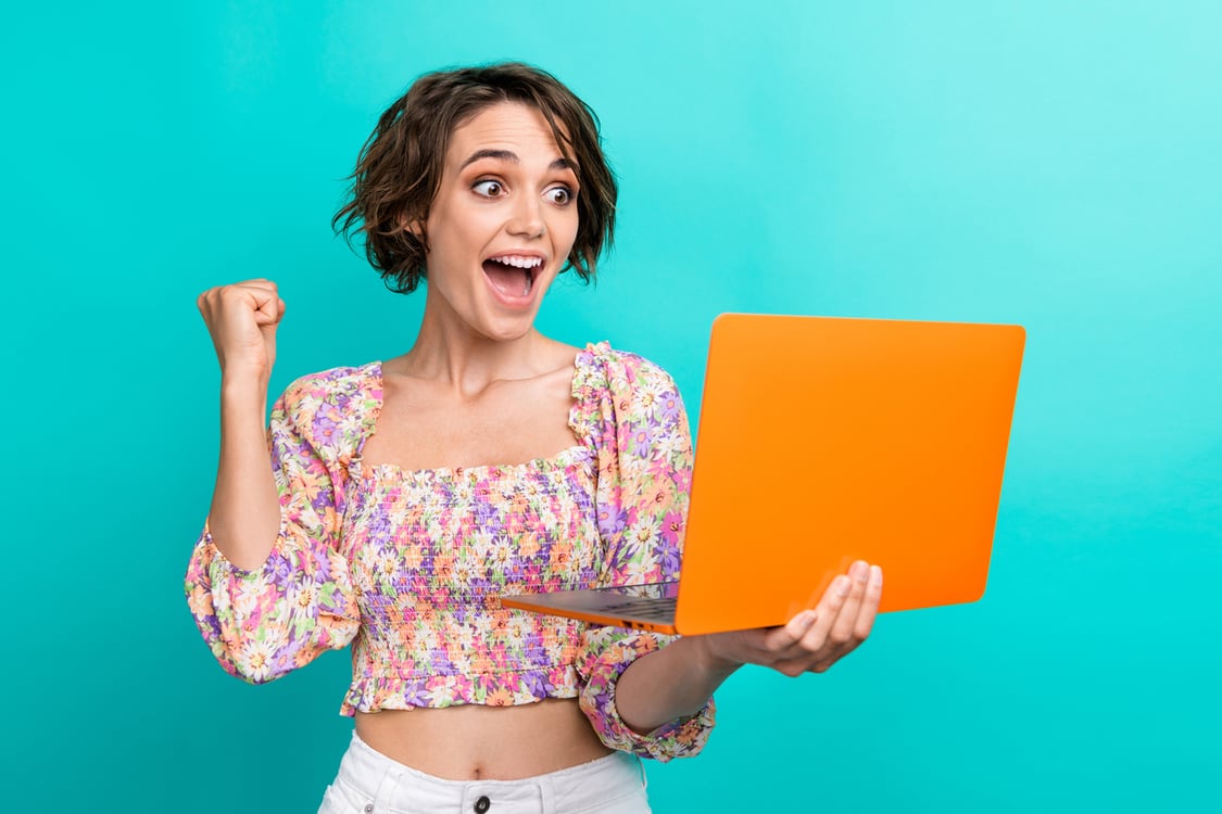 mulher comemorando com o notebook na mão 