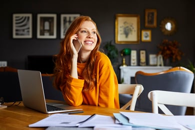 Mulher ruiva falando ao telefone em home office