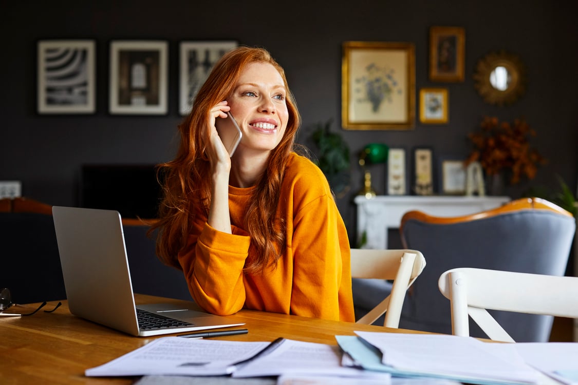 Mulher ruiva falando ao telefone em home office