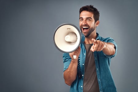 homem falando em um megafone e apontando para frente