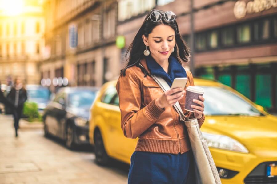 mulher olhando o celular na rua